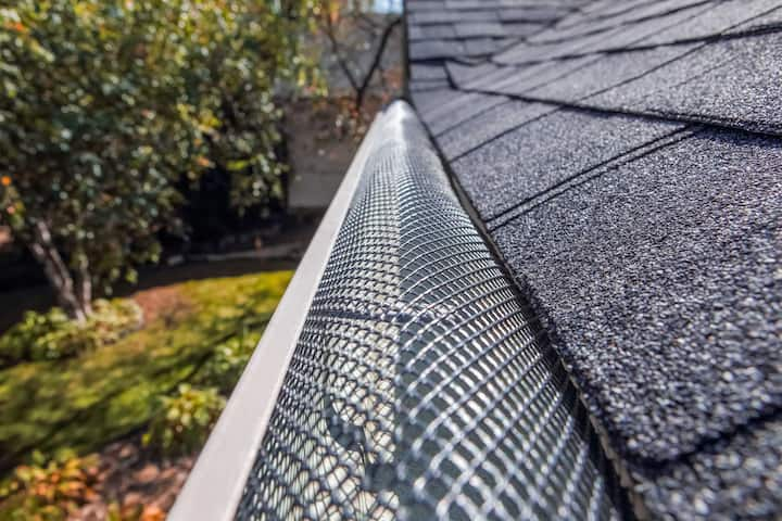 A contractor demonstrating the effectiveness of a gutter guard to a potential client in Winston Salem